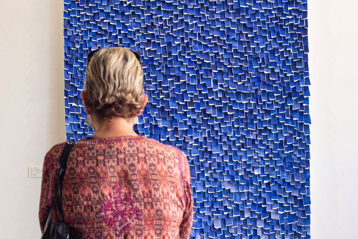 Gallery guest looking at a blue artwork by Karla Nixon