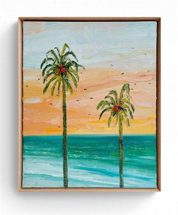 framed painting depicting palm trees against a backdrop of turquoise sea and peach sky