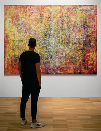Man standing in front of an extra large abstract oil painting in a gallery
