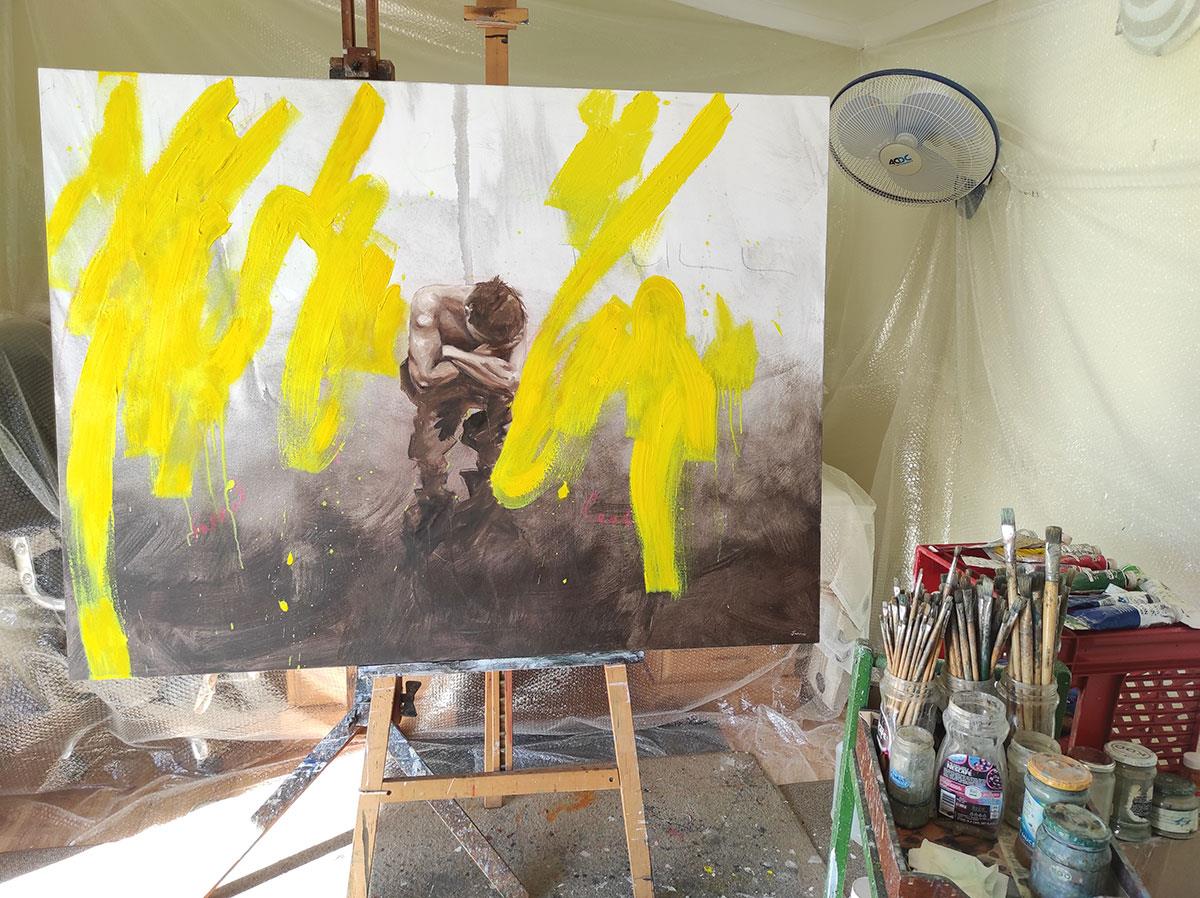 extra large painting of a crouching man with yellow graffit paint