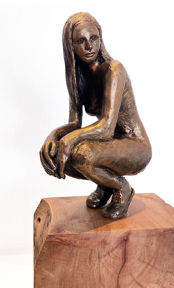 sculpture of a nude female figure crouching