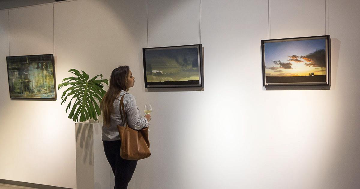 Gallery visitor looking at paintings by Catherine Ocholla