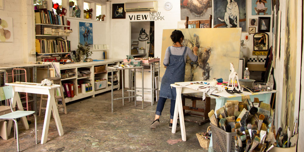 Pascale Chandler sketching a horse and rider against a yellow background in her studio